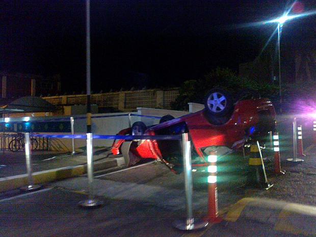 Mulher capota carro na entrada do estacionamento.